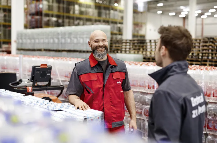 Ein Logistik Mitarbeiter in Arbeitskleidung steht in einem PENNY Lager 